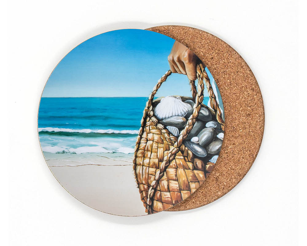 Of the Sea coaster by Graham Young Artist — a woven kete filled with shells and beach stones, held up against the ocean and sky