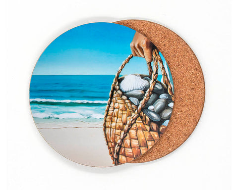 Of the Sea coaster by Graham Young Artist — a woven kete filled with shells and beach stones, held up against the ocean and sky